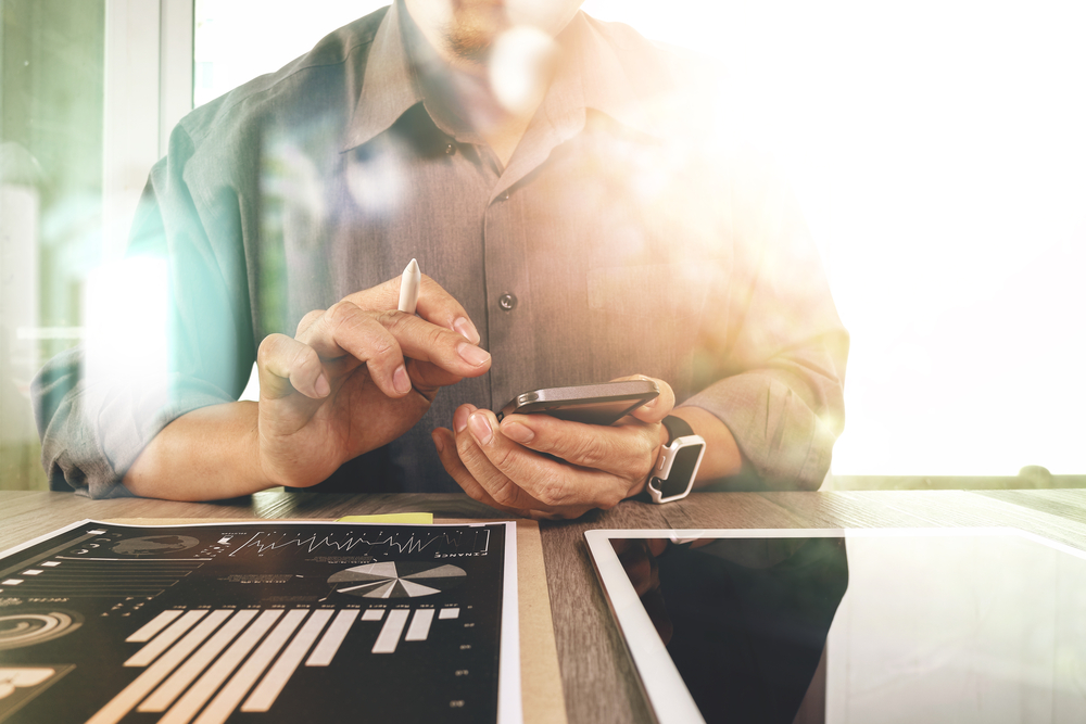 Businessman working with digital tablet computer and smart phone with digital business strategy layer effect on wooden desk as concept