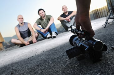 three young man siting on ground while modern video camera recording.jpeg